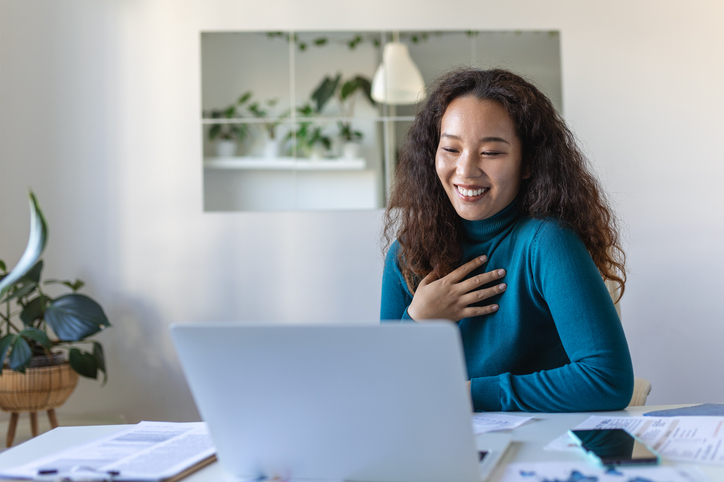 Asian businesswoman on a video call while sitting at her desk. Shot of an attractive young woman using her laptop to make a video call at home